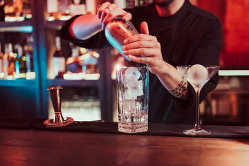 Detail of unknown bartender mixing cocktail in pub
