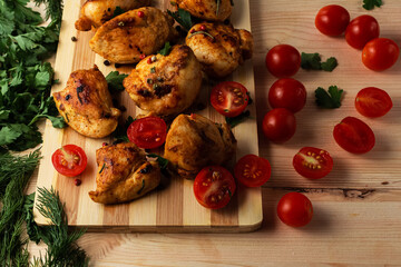 fried chicken fillet with tomatoes seasoned with pepper and herbs cutting Board