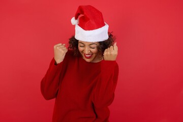 Caucasian brunette woman rejoicing her success and victory clenching her fists with joy. Lucky woman with hair bun being happy to achieve her aim and goals. Positive emotions, feelings.