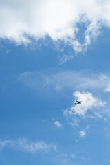 The airplane flies against the background of clouds in the blue sky
