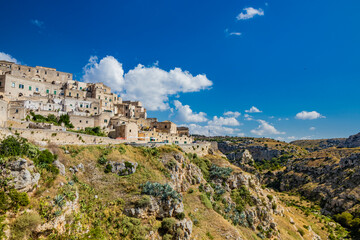 Fototapeta na wymiar Matera, Basilicata, Italy - Panoramic view from the top of the Sassi of Matera, Barisano and Caveoso. The ancient houses of stone and brick, carved into the rock. The ravine in the background.