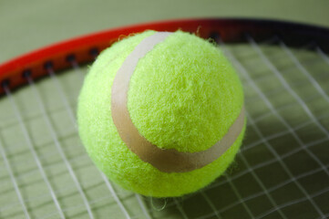 Tennis racket with ball on a green background