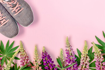 Gray women's summer sneakers and pink purple flowers lupine on pink background. Women's shoes....