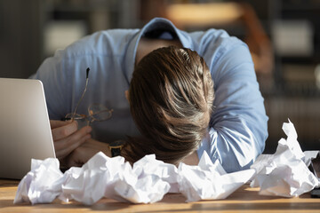 Exhausted male employee fall asleep doze off at desk at workplace overwhelmed with work amount....