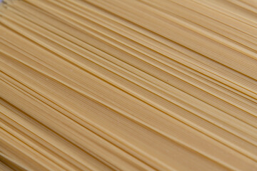 Abstract food background of raw uncooked spaghetti pasta made from milled durum wheat. Selective focus. Copy space for your text. Italian cuisine theme.