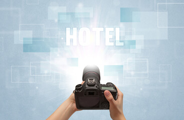 Close-up of a hand holding digital camera with HOTEL inscription, traveling concept