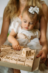 Little girl playing with wooden ABC blocks. Plastic-free wooden zero waste kids toys for safe and sustainable gifting. Eco friendly, plastic free toys for toddler.