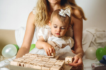 Little girl playing with wooden ABC blocks. Plastic-free wooden zero waste kids toys for safe and sustainable gifting. Eco friendly, plastic free toys for toddler.