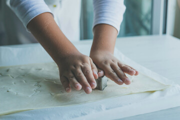 Child hands making christmas tree shaped cookies in fresh dough
