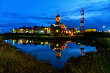 Fototapeta na wymiar Russian orthodox church in Yamburg - small town in north of Russia at night time with reflection in water.