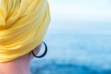 Female with a yellow scarf enjoying the sea view - concept: fight against cancer