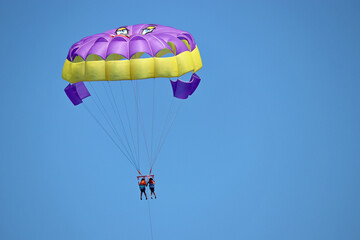 Parasailing on the sea, two girls on parashute in blue sky. Concept of vacation, extreme sports on a beach