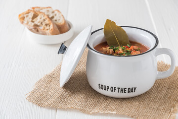 Bowl with Solyanka, a spicy and sour soup of Russian origin, on white wooden table. Soljanka is popular in East European countries and East Germany.