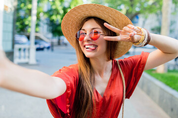 Cute lady  in stylish hat making selfie while walking outdoor in summer weekends. Good mood. Lifestyle image.