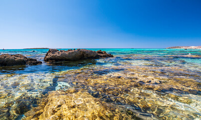 Elafonisi Crete Beach view to crystal clear water with nature rocks at the background
