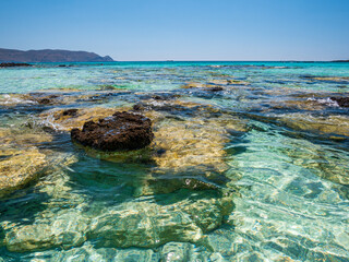 Elafonisi Crete Beach view to crystal clear water with nature rocks at the background