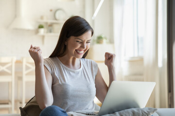 Positive female student in casual wear overjoyed about admission to university after receiving good news by email. Happy young graduate with laptop celebrating getting job after reading notification