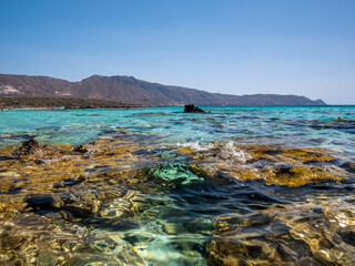 Elafonisi Crete Beach view to crystal clear water with nature rocks at the background