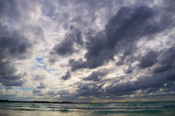 Stormy dark clouds above the sea with sandy beach and curling waves
