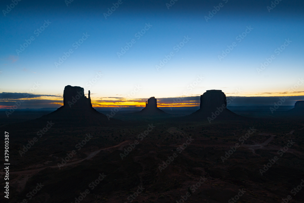 Wall mural Rock outcrops of Monument Valley silhouetted ar sunset