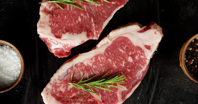 Steak striploin raw beef with rosemary and spices rotates.