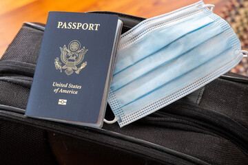 Covid 19 face mask and a passport sitting on top of a suitcase