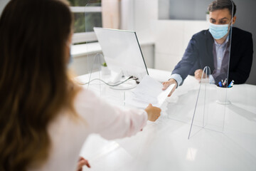 Consultant Giving Contract Papers Through Sneeze Guard