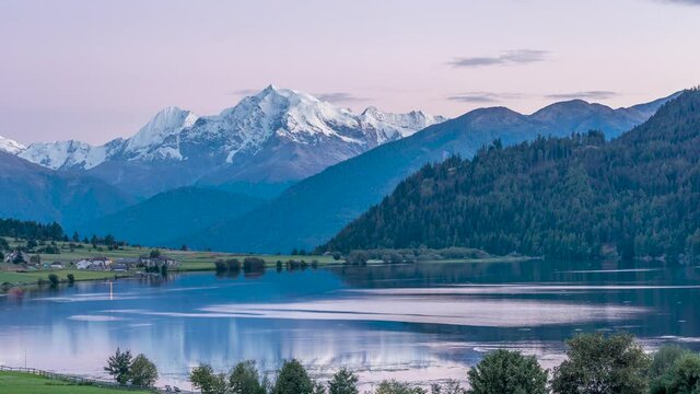 Sunset on Lago della Muta lake with the snowy Mount Ortles in the background, South Tyrol, Italy, reflected in the water. Time lapse motion