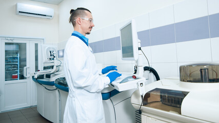 Laboratory assistant in rubber gloves working with a modern immunochemistry analyzer