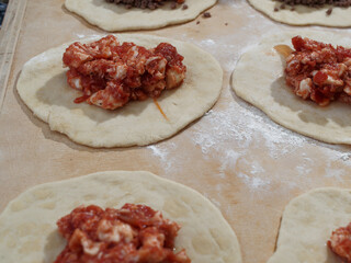 Preparations for a panzerotto, a specialty of southern Italian cuisine. Minced meat, mozzarella and tomato poured as a filling on the dough.