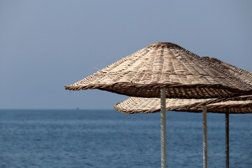 Wicker parasols on blue sea background. Beach umbrella, vacation concept