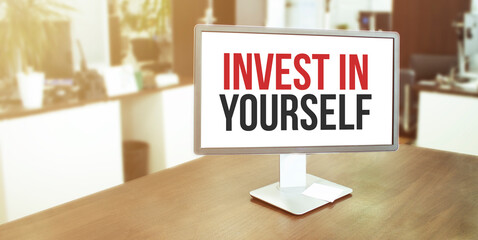 Monitor in modern office with INVEST IN YOURSELF text on the screen