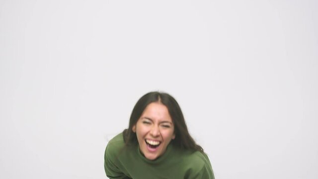 Young cute woman laughs happily and has fun keeping hands on stomach