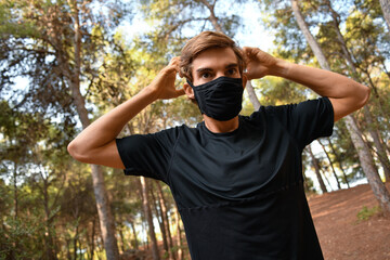 Naklejka premium Joven atleta ajustándosela la mascarilla en el bosque