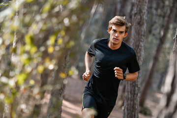 Young athlete running in the forest with a black outfit
