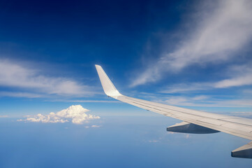 Naklejka na ściany i meble Aussicht aus einem fliegenden Flugzeug über den Wolken mit blauem Himmel als Hintergrund mit Textfreiraum
