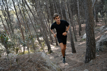 Young athlete running in the forest with a black outfit