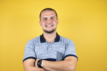 Russian man standing over insolated yellow background happy face smiling with crossed arms looking at the camera. Positive person.