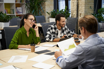 Young successful multiracial business team sitting at the desk and working together in the modern office