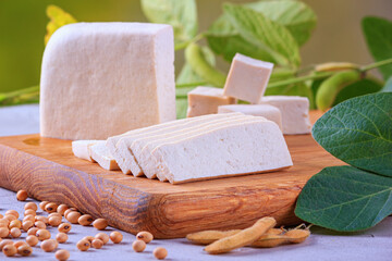 Tofu, also known as bean curd, diced on a wooden cutting board, closeup with selective focus