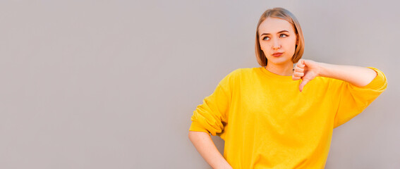 European woman shows disapproval sign, gives thumb down gesture, dislikes something, has disgusting...