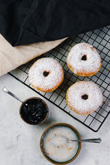 Baker sprinkles sweet ring  donuts with powder sugar and sugar glaze