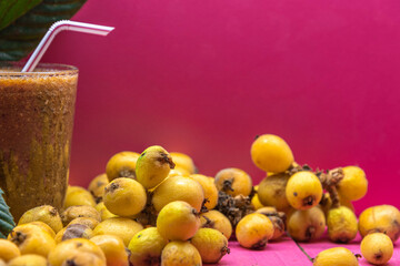 Fresh loquat fruits and juice on pink background