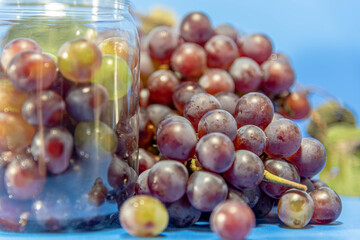 Grape bunches in a bowl and on the table on blue and defocused background