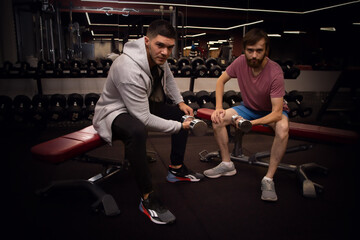 beginner sport man and personal trainer sit on bench with dumbbells and sports exercise. assisting...