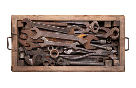 Collection of rusty vintage tools such as wrenches, spanners, pincers and other in a wooden box isolated  on white background, top view