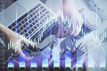Double exposure of businesswoman hands typing on computer and financial graph hologram drawing. Stock market analysis concept.