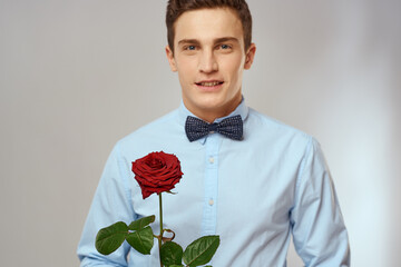 Portrait of a handsome man with a red rose and in a light shirt cropped view