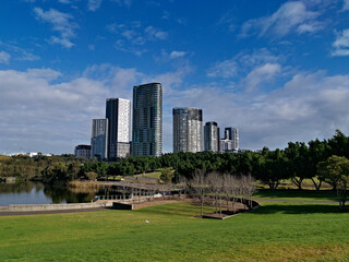 Fototapeta premium Beautiful view of a lake with reflections of luxury high-rise building, blue sky, clouds, and trees on water, lake Pavillion, Sydney Olympic park, Sydney, New South Wales, Australia 