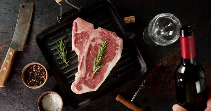 Steak raw beef t-bone in a frying pan with a glass of wine. 